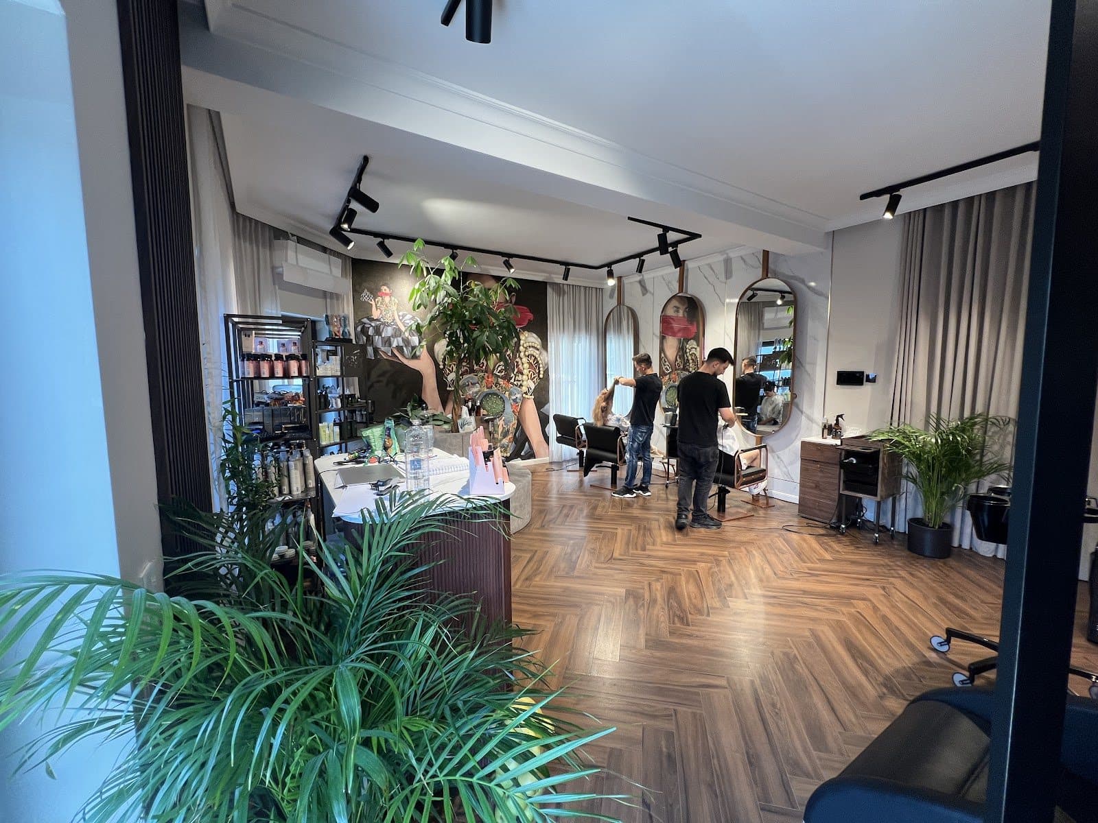 Stiliștii Studio di Bellezza lucrând în salonul din Sibiu, cu plante și pereți de marmură